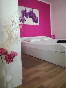 - une chambre avec un lit blanc et un mur rose dans l'établissement Dama Apartment, à Biograd na Moru