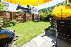 un patio trasero con una sombrilla amarilla, sillas y una valla en Ferienhaus Vier Jahreszeiten en Bad Urach