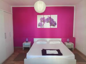 - une chambre avec un mur rose et un lit blanc dans l'établissement Dama Apartment, à Biograd na Moru