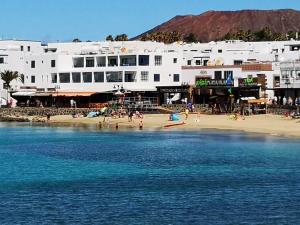 un groupe de personnes sur une plage près de l'eau dans l'établissement Apartamento Anaca, à Playa Blanca