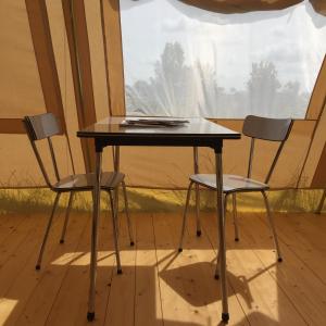 twee stoelen en een tafel voor een raam bij VierVaart Tent in Groede