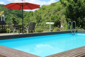 a pool with a red umbrella and chairs and a table at Hotel Haus Appel in Rech