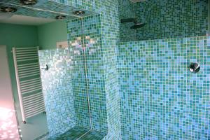 a blue tiled bathroom with a shower with a glass door at Fare Bambou in Gujan-Mestras