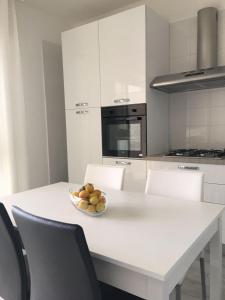 a white kitchen with a bowl of fruit on a white table at Bianco&Nero 141 Apartament in Margherita di Savoia