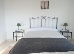 a bedroom with a large bed with two lamps at Alojamiento Rural El Orégano in Campillos