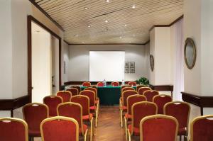 a conference room with red chairs and a white screen at Hotel Torino in Rome