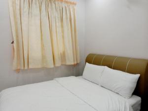 a bedroom with a bed with white sheets and a window at Taiping Cozy Homestay II in Taiping