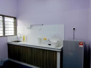a kitchen with a counter with a sink and a refrigerator at Taiping Cozy Homestay II in Taiping