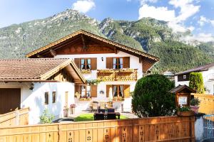 une maison avec une clôture en face d'une montagne dans l'établissement Ferienwohnungen Alpspitzecho, à Garmisch-Partenkirchen
