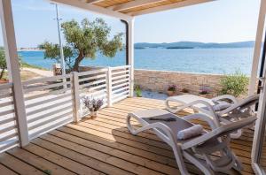 a deck with two chairs and a table and a view of the water at Camp San Antonio in Biograd na Moru