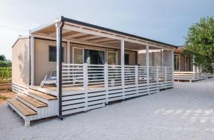 een modulair huis met een veranda en een stoel bij Camp San Antonio in Biograd na Moru