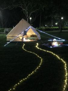 une tente avec des lumières sur l'herbe la nuit dans l'établissement Glamping Kaki - Medium Bell Tent, à Singapour