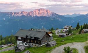 ein Haus auf einem Hügel mit Bergen im Hintergrund in der Unterkunft Sattleggers Alpenhof & Feriensternwarte in Berg im Drautal