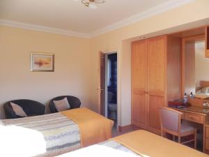 a hotel room with two beds and a desk at Shelmalier House in Athlone
