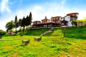 a house on a hill with tables and chairs in a field at Akamoy Boztepe Hotel & restaurant in Ordu