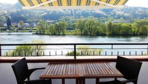 ツェル・アン・デル・モーゼルにあるLuxus Ferienhaus Inselblickのテーブルと椅子、川の景色を望むバルコニー