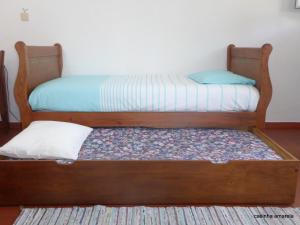 a bed with a wooden frame in a room at Casinha Amarela in Sintra