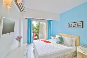 a bedroom with a bed and a tv and a window at Kiraz Butik Hotel in Alacati