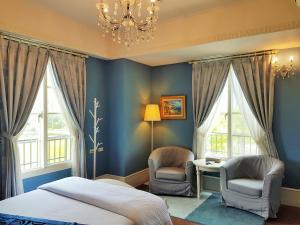 1 dormitorio con paredes azules, 2 sillas y 1 cama en Haut Rhin Villa, en Zhuangwei