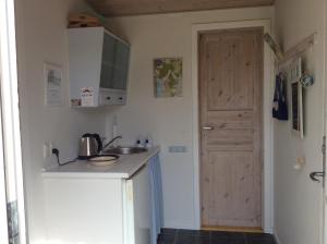 une petite cuisine avec un évier et une porte. dans l'établissement Strandværelserne, à Ebeltoft