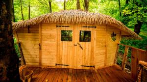 a wooden cabin with a thatch roof on a deck at Treehouse pod Jestedem in Světlá pod Ještědem