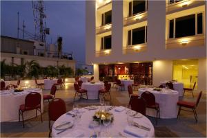 un restaurante con mesas y sillas blancas y un edificio en Vivanta Vijayawada, MG Road, en Vijayawāda
