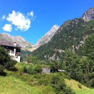 a house on a hill with mountains in the background at Pensione Genzianella in Alagna Valsesia