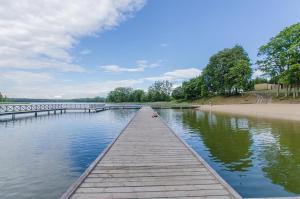 a wooden dock in the water next to a beach at Karczma u Wallenroda in Ryn +8 photos