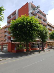 ein Hotelgebäude mit einem Baum davor in der Unterkunft Hotel Chris'tel in Le Puy en Velay