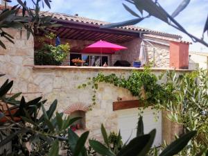 una persona con un paraguas rosa en un edificio en VILLA ARTEMIA Maison vigneronne - chambre d hôtes-B&B-piscine et spa, en Sigean