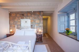 a bedroom with a white bed and a stone wall at Theologos Houses in Grikos