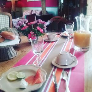 einen Tisch mit einem rosa und weißen Tischtuch mit Obst darauf in der Unterkunft Au Bonheur De Ce Monde in Boudreville