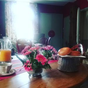einen Tisch mit Blumen und einen Korb mit Brot und Orangensaft in der Unterkunft Au Bonheur De Ce Monde in Boudreville