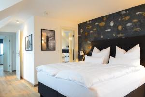Schlafzimmer mit einem großen weißen Bett mit einem schwarzen Kopfteil in der Unterkunft Haus Sathurn in Helgoland