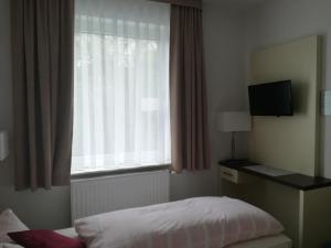 a bedroom with a bed and a window with a television at Zeesener Gasthof in Königs Wusterhausen
