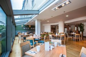 a restaurant with wooden tables and chairs and windows at Drayton Manor Hotel in Tamworth
