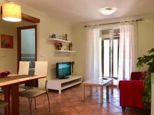 - un salon avec une télévision et une table dans l'établissement La Felicidad Apartamento en Dénia, à Dénia