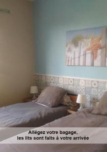 a bedroom with two beds and a picture on the wall at Au cèdre bleu in Saint-Martin-Boulogne