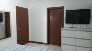a bedroom with a bed and a television on a dresser at London House in São José