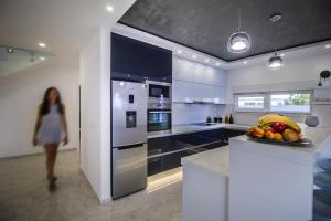 马卡尔斯卡Villa Lacus的一位在厨房里一边吃水果一边散步的女人