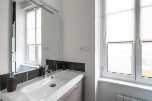 La salle de bains blanche est pourvue d'un lavabo et d'un miroir. dans l'établissement Zen et design, proche Cité Corsaire, à Saint-Malo