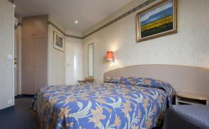 a hotel room with a bed with a blue and white bedspread at Hôtel Transcontinental in Paris