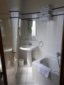 y baño blanco con lavabo, bañera y lavamanos. en Hôtel Transcontinental, en París