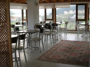 un comedor con mesas, sillas y ventanas en Villa Bagci Hotel, en Eceabat