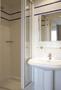 a bathroom with a sink and a shower and a mirror at Hôtel Transcontinental in Paris