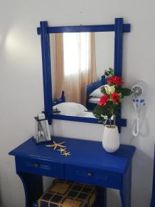 a blue dresser with a mirror and a vase with flowers at Aiantas in Ermoupoli