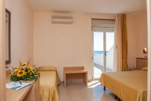 a hotel room with two beds and a vase of flowers at Hotel Cristalda in Vieste