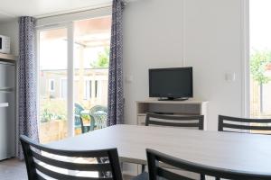 a dining room with a table and chairs and a television at Camping Coll Vert in Pinedo