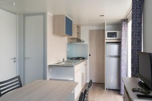 a small kitchen with a table and a refrigerator at Camping Coll Vert in Pinedo