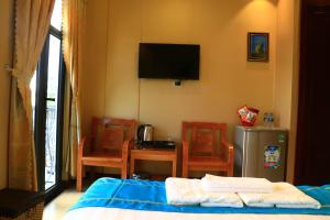 a bedroom with a bed and chairs and a television at Hồng Hạc Hotel in Tuy Hoa